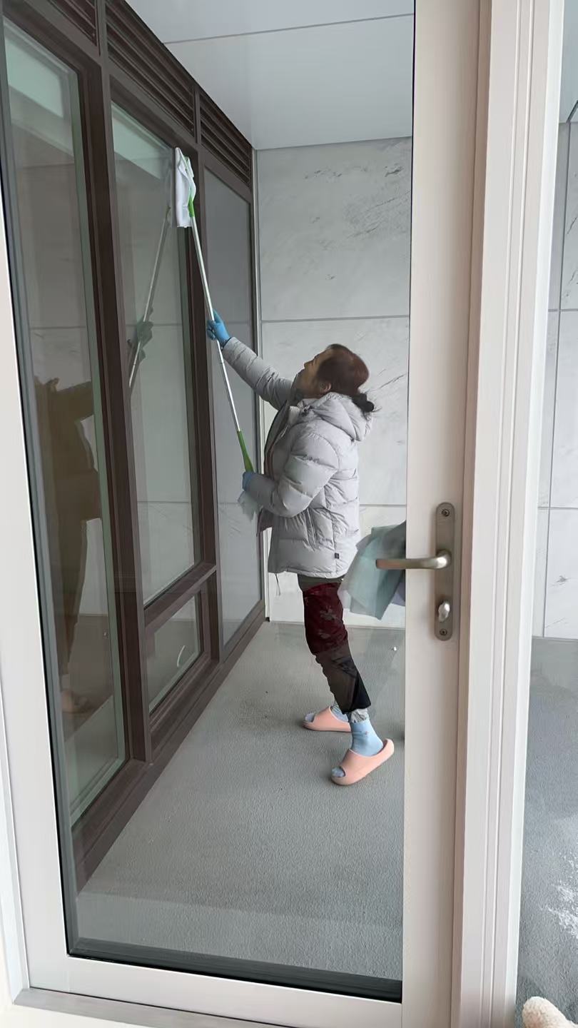 Cleaning professional wiping glass doors with a mop in a modern entryway