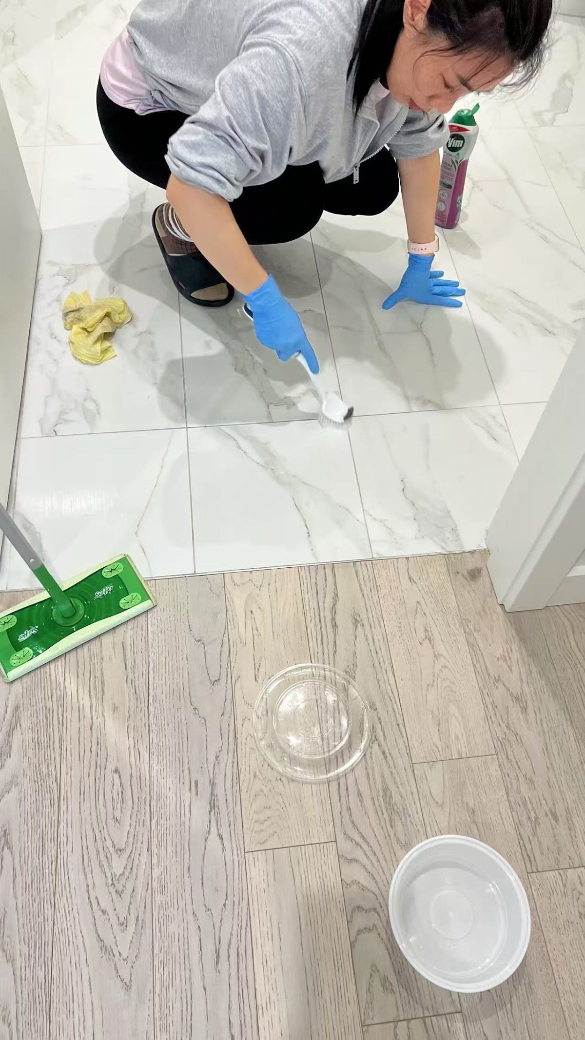 Professional cleaner scrubbing tile floors by hand with cleaning supplies