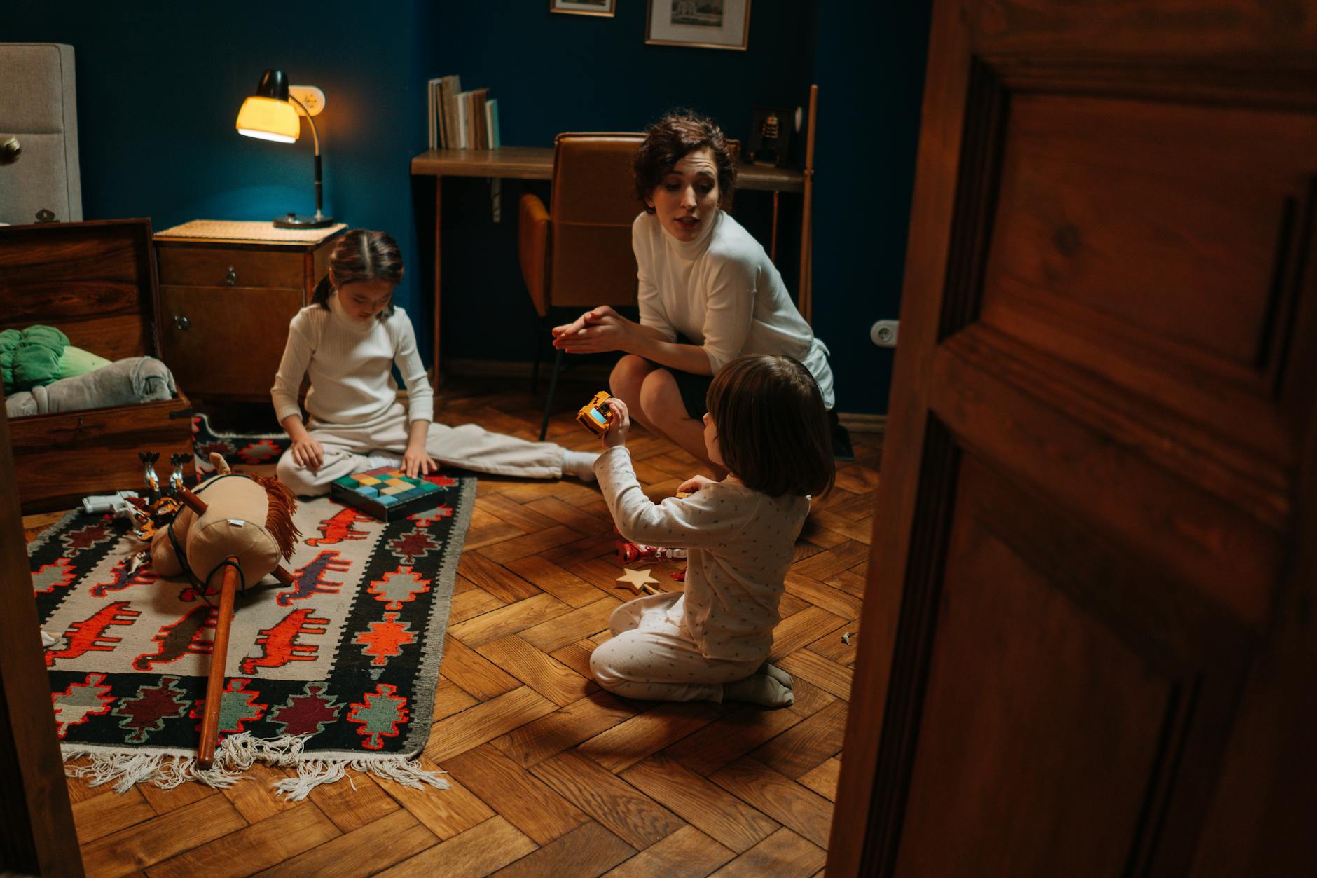 Caregiver sitting on floor playing with children in a warm home setting